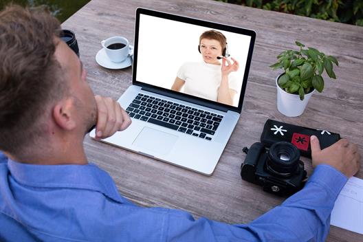 Mann sitzt vor einem Laptop und führt ein Video-Telefonat